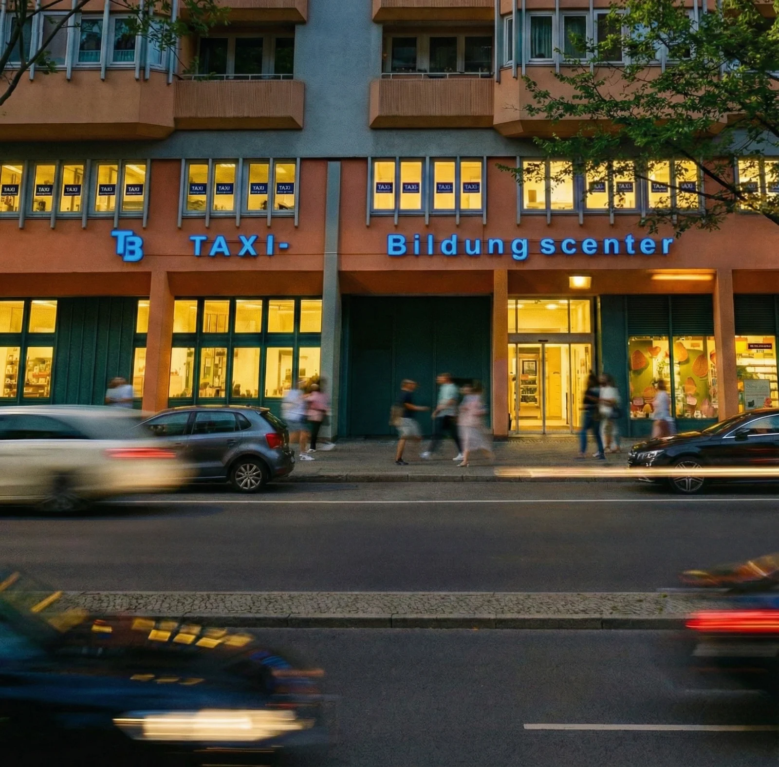 Das Taxi-Bildungscenter Berlin am Abend mit blauem Schriftzug und beleuchtetem Eingang.